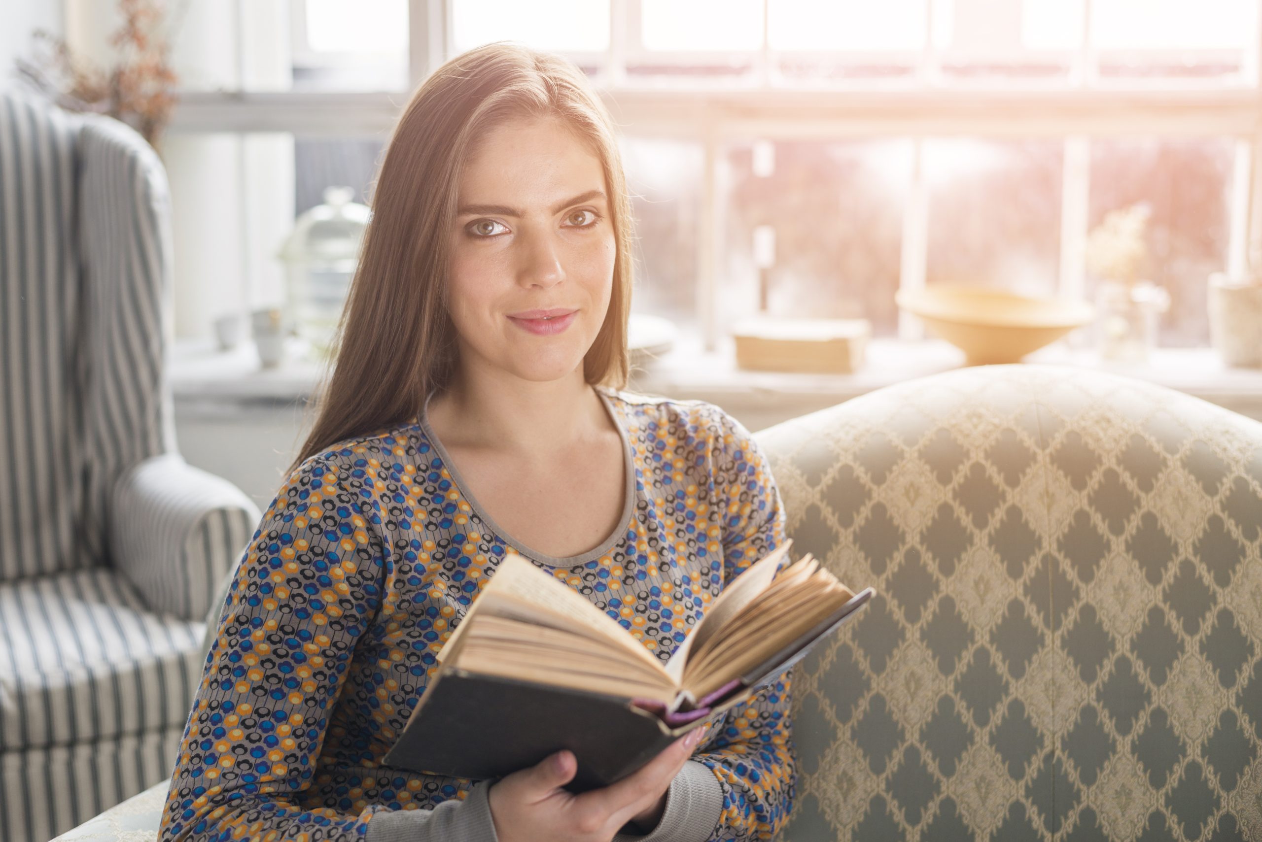 pretty-young-woman-holding-book-hand-looking-camera